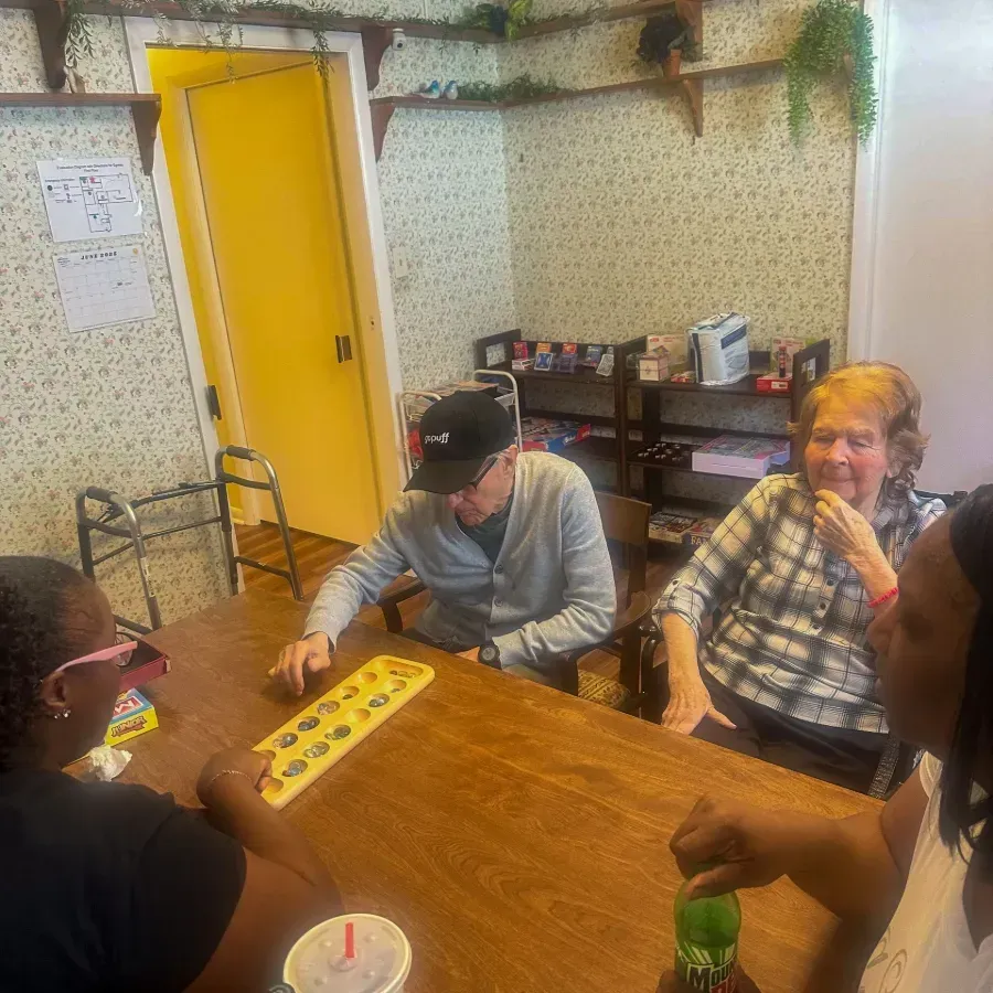 People sitting around a wooden table playing a board game in a cozy room