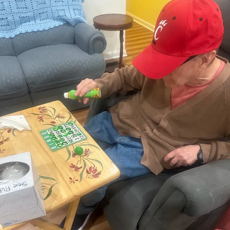 Person in red cap reaching toward a decorated tray table beside a couch in a living room.