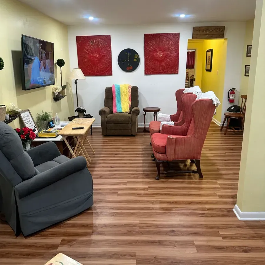 Cozy living room with recliners, wall art, a TV, and wood floors