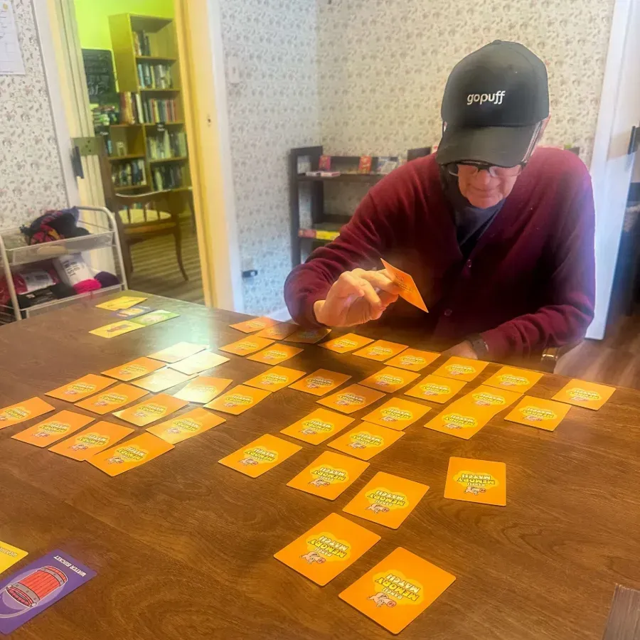 Person sorting orange cards on a wooden table in a bright room