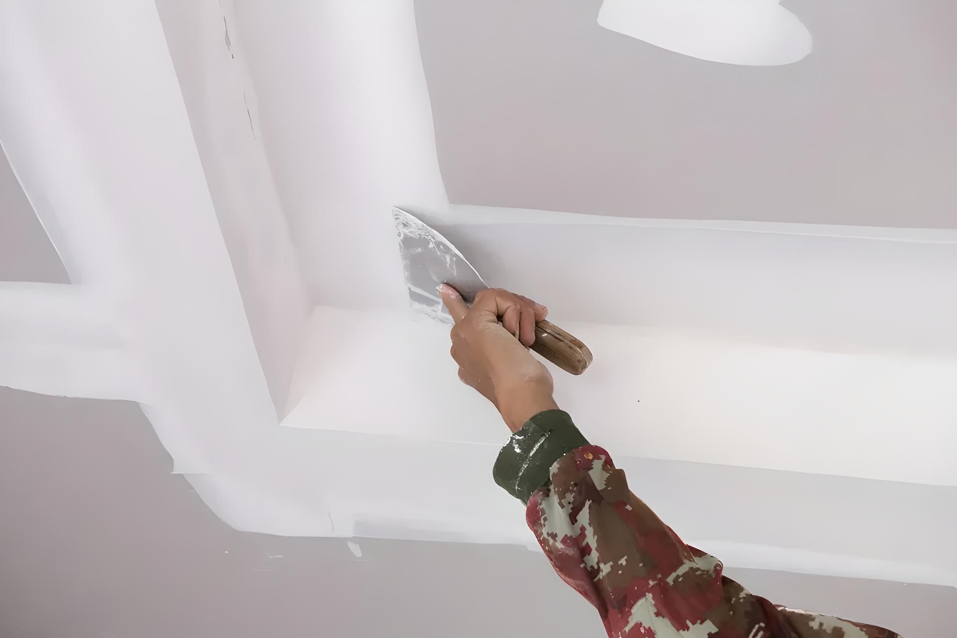 A person is spackling over drywall with a putty knife