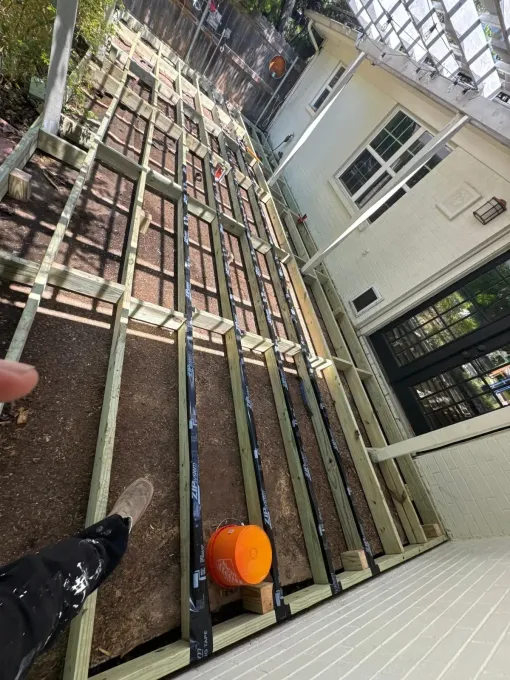 A person is standing on a wooden deck under construction.