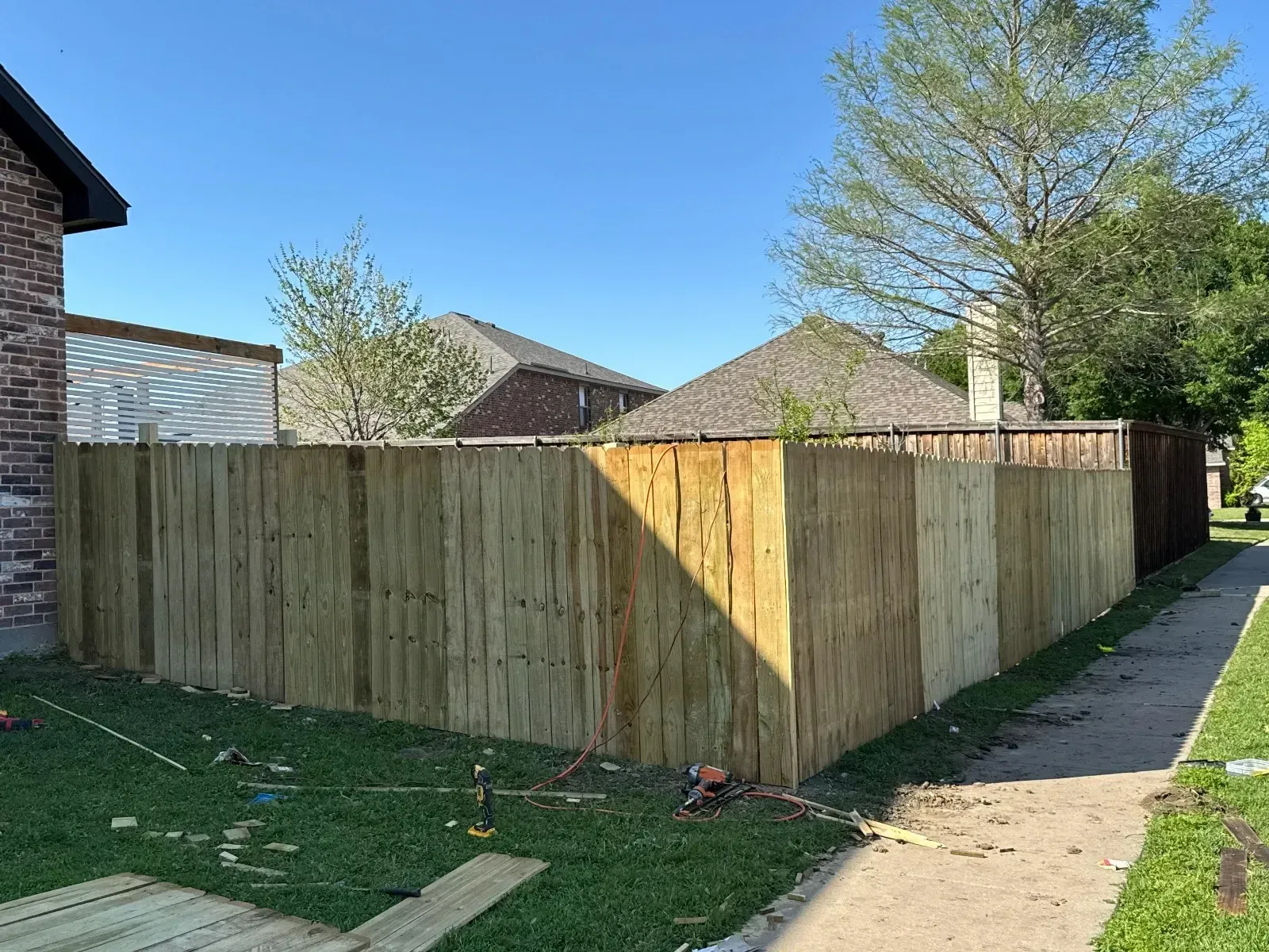 A wooden fence is being built in the backyard of a house.