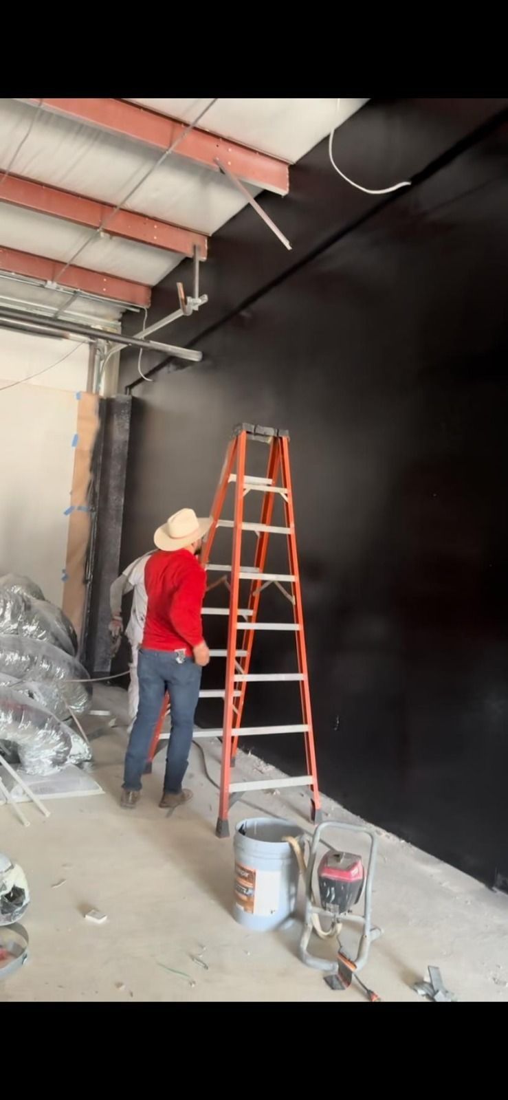 A man is standing on a ladder painting a wall.
