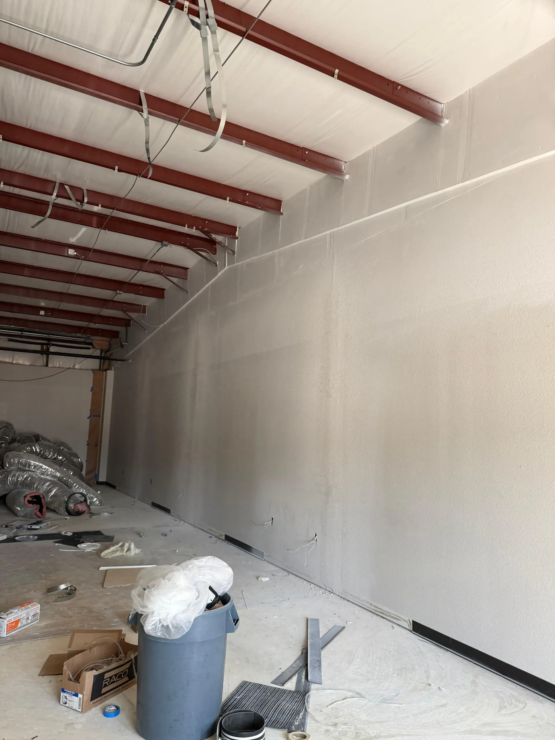 A room with a large wall and a trash can in it