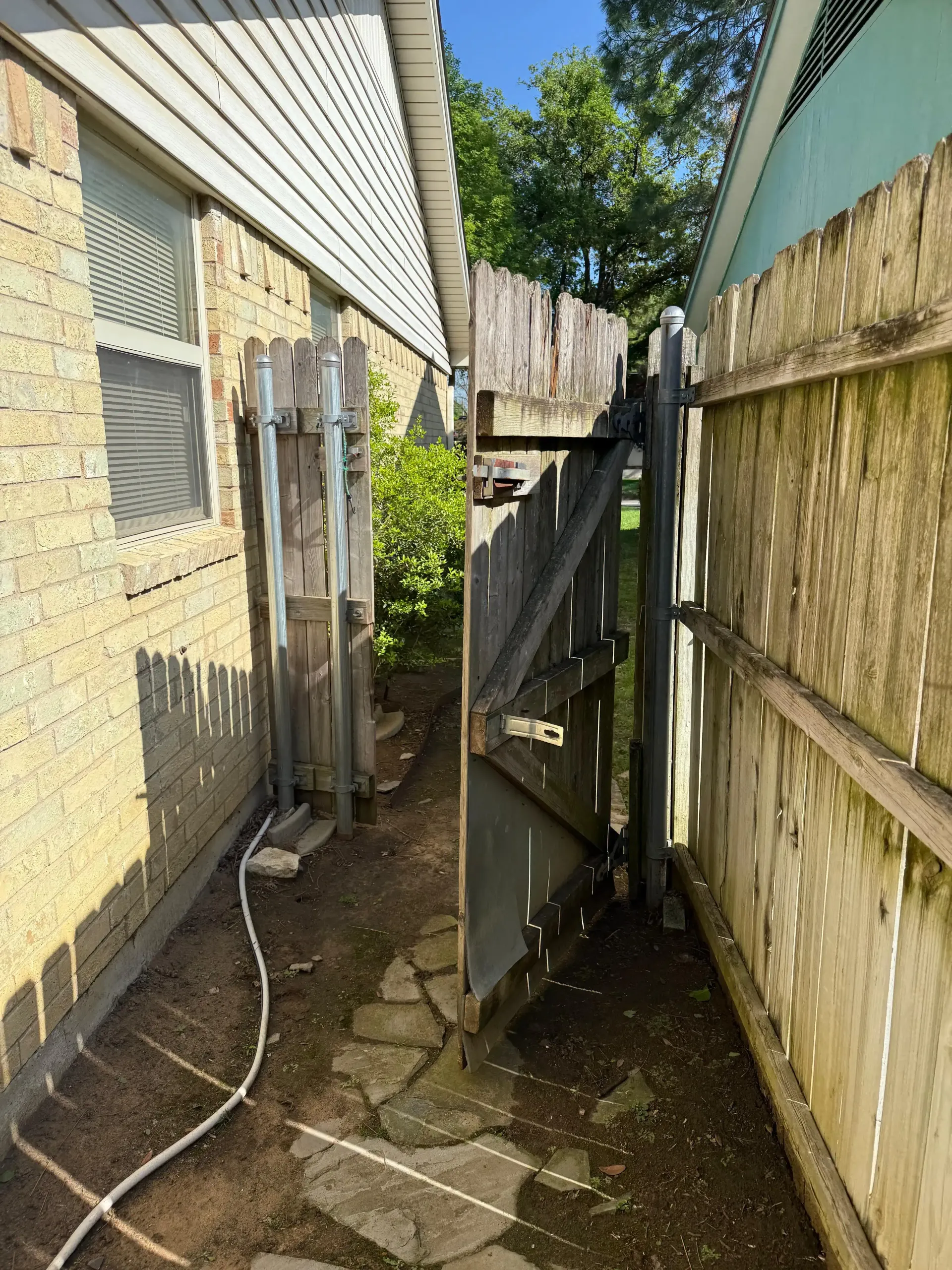 A hose is connected to a wooden fence next to a house.
