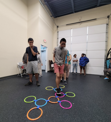 Two boys stepping through colorful hoops in an indoor gym activity course