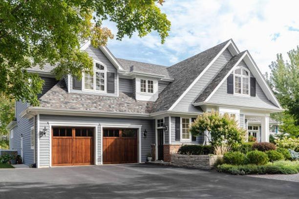 A large house with two garage doors and a driveway.