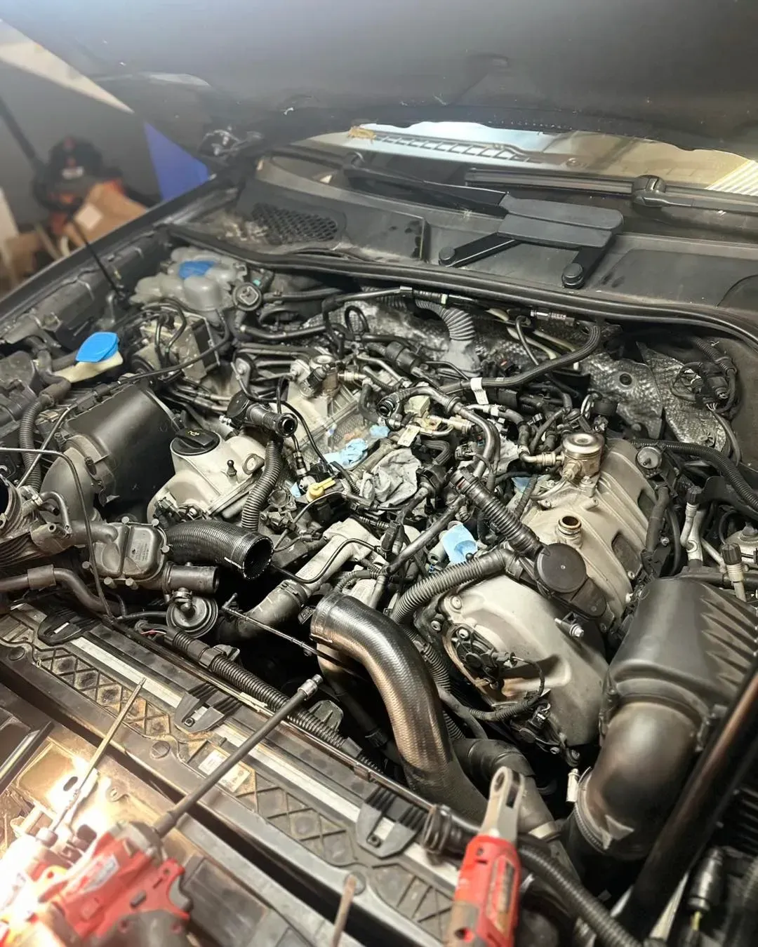 Car engine with parts removed, exposed in a garage setting | Konstant Autowerks