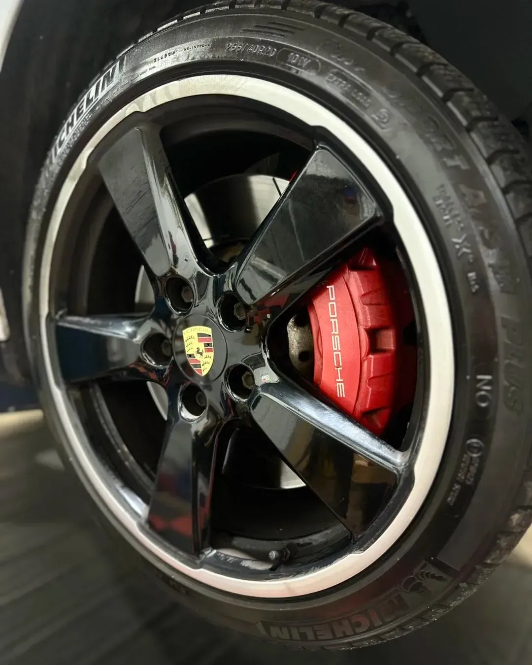 Black Porsche wheel with red brake caliper and Michelin tire | Konstant Autowerks