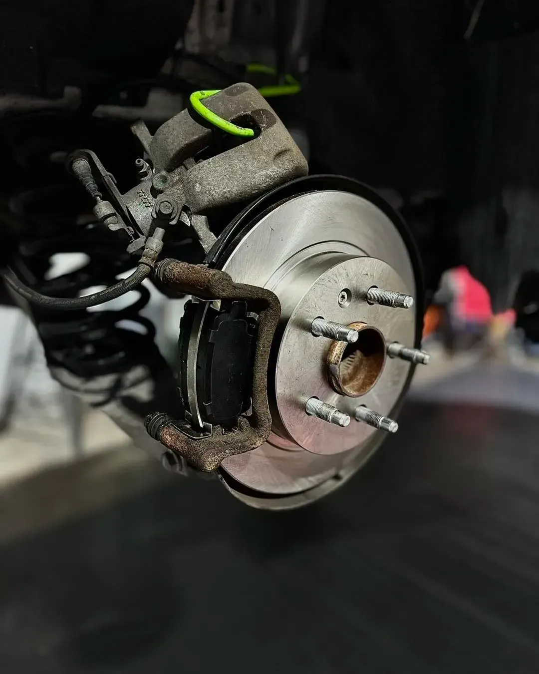 Car's rear brake disc and caliper are exposed | Konstant Autowerks