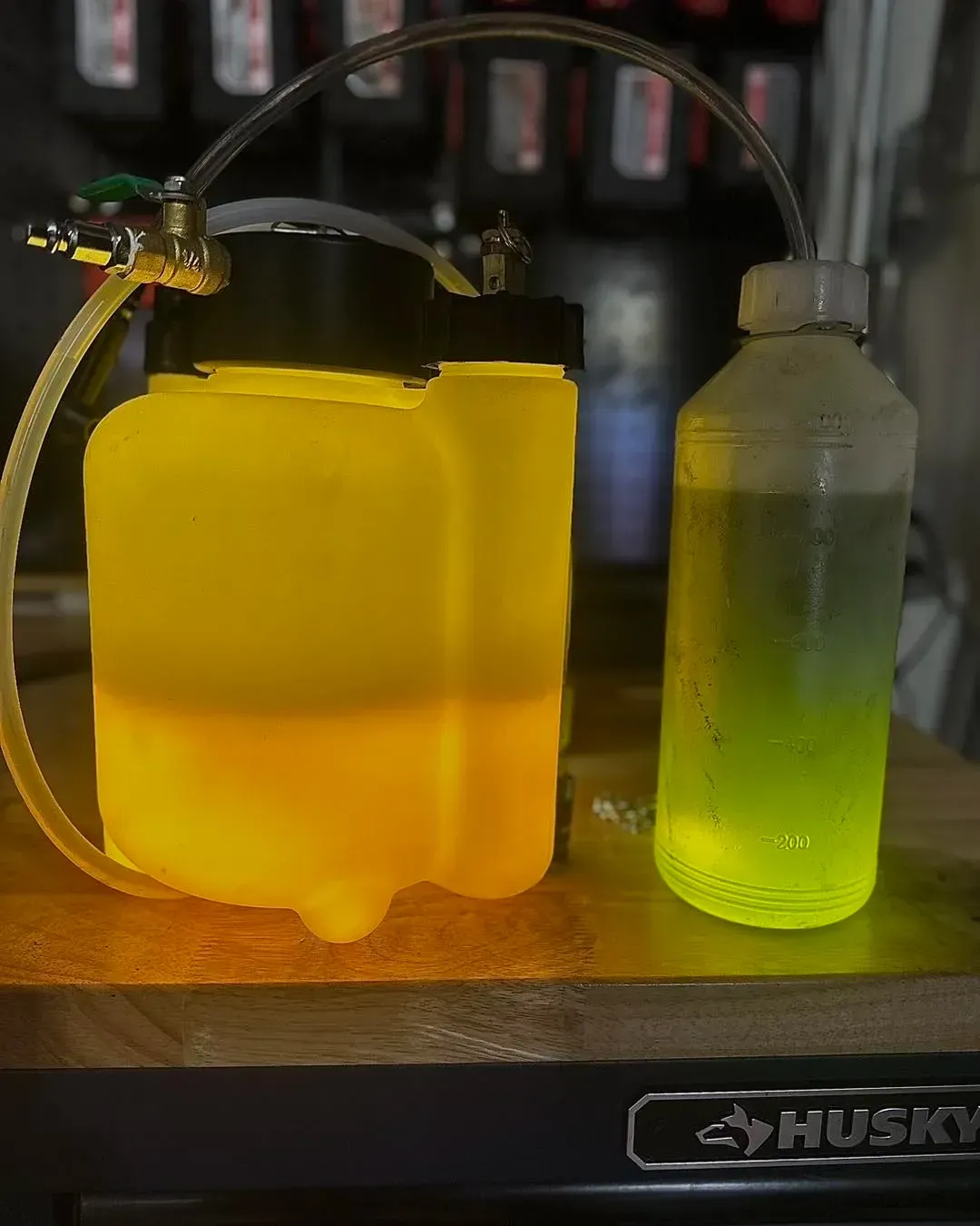 Yellow and green liquids in clear containers connected by a tube | Konstant Autowerks
