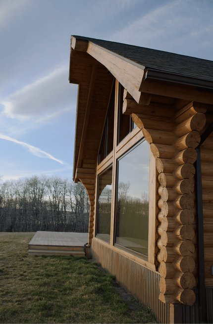 Log cabin exterior with large reflective window under a blue sky