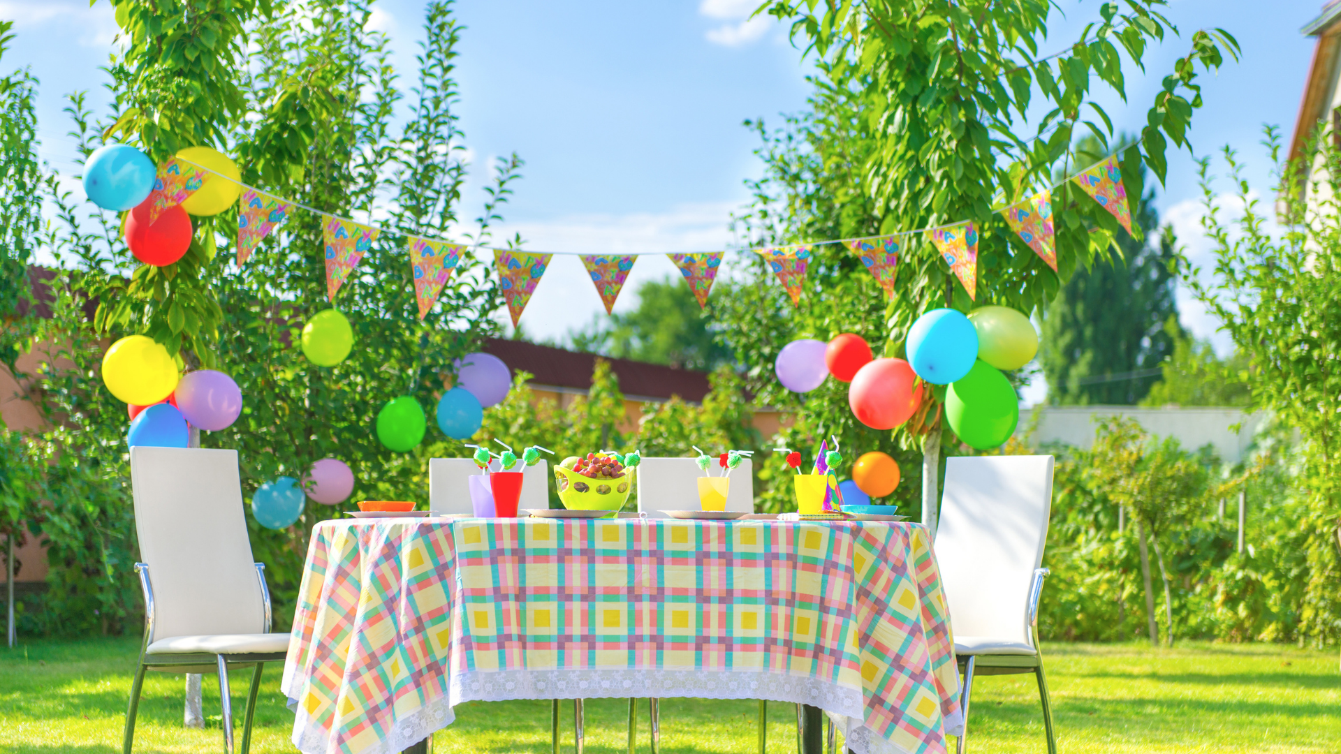 A table and chairs are set up for a birthday party in the backyard.