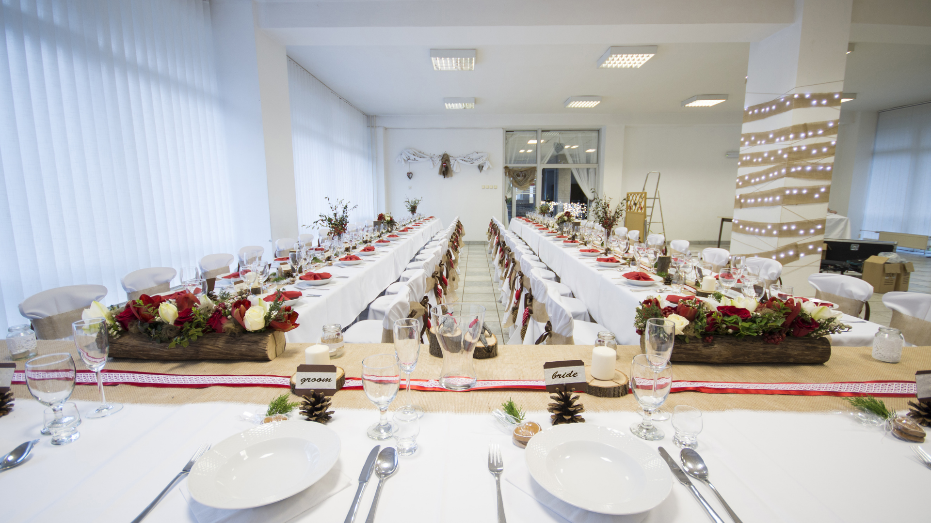 A long table with plates , utensils , glasses and flowers on it.