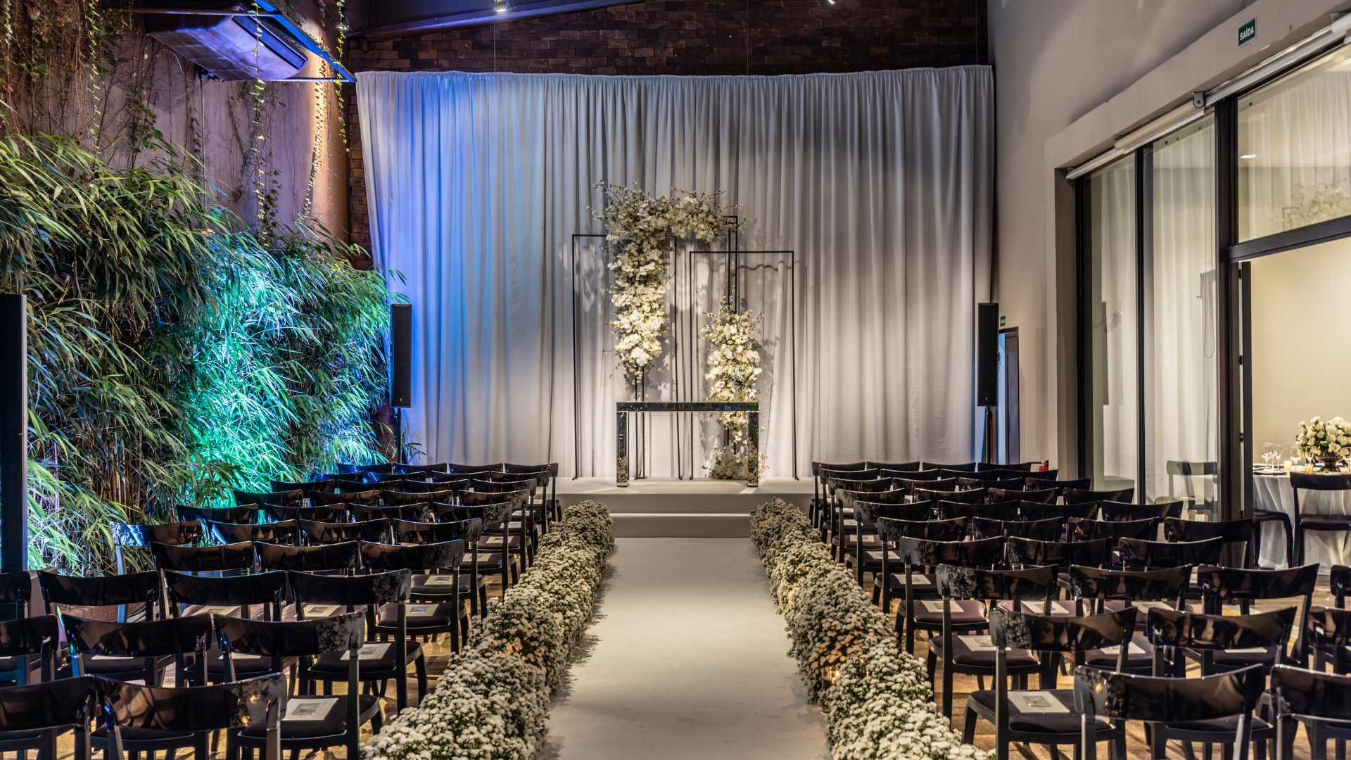 A large room with rows of chairs and a stage with flowers on it.