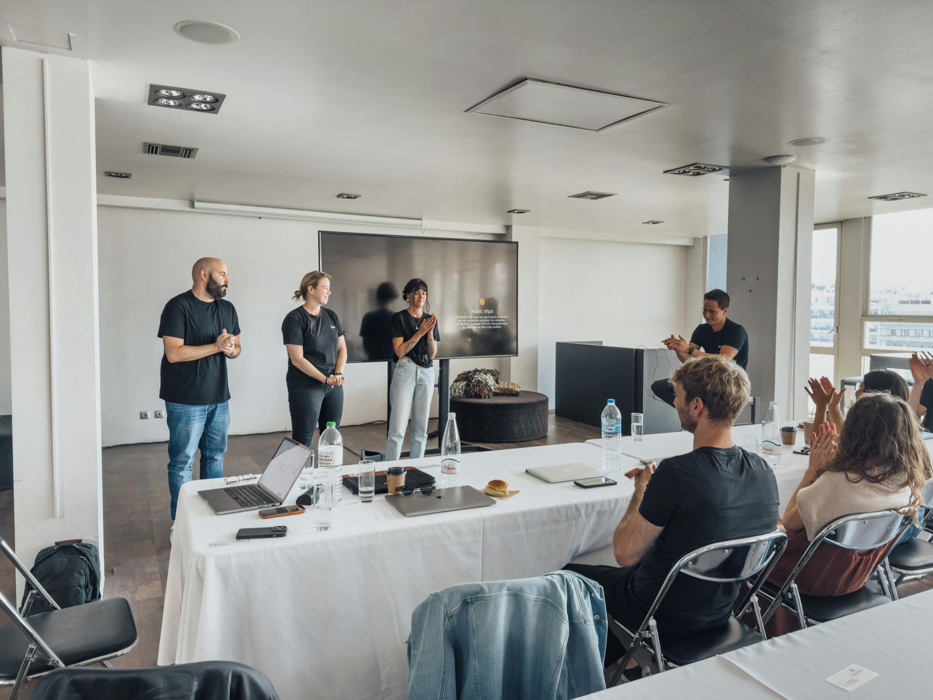 A group of people are standing around a long table in a conference room.
