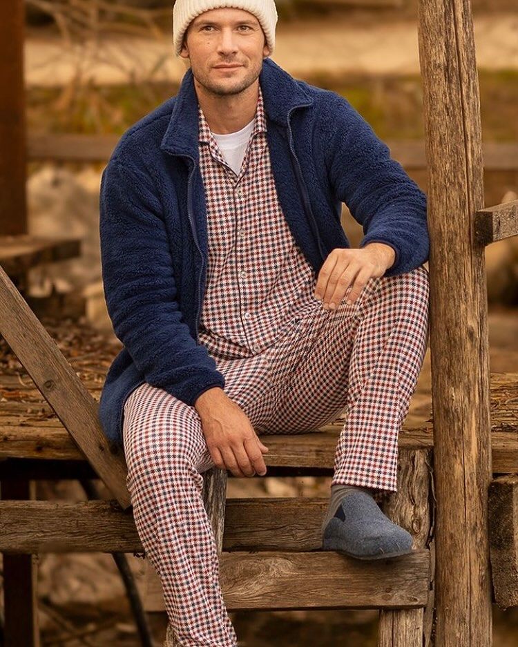 Un uomo in pigiama è seduto su una scala di legno.