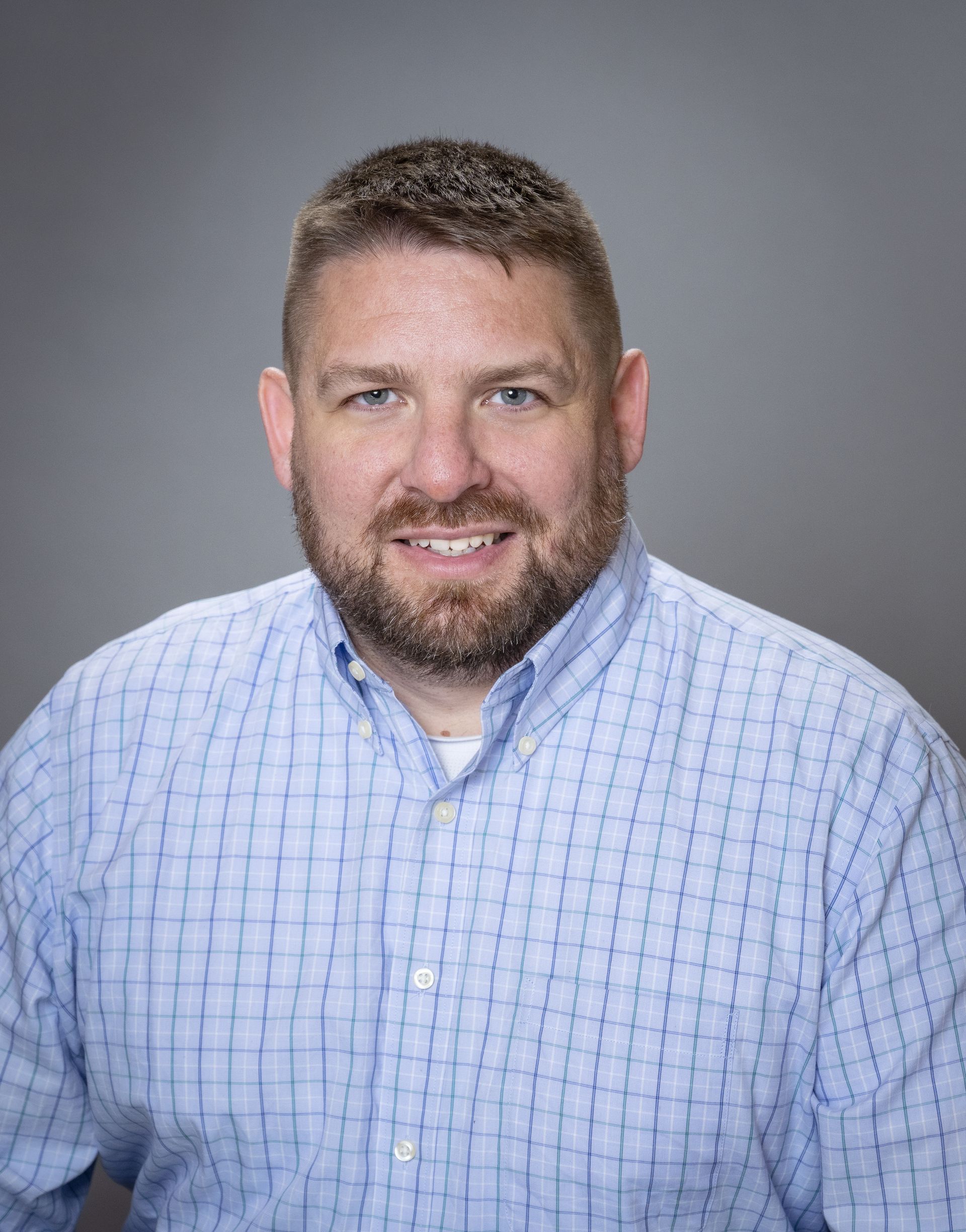 A man in a suit and tie is standing in front of a body of water.