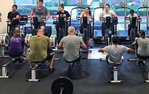 A group of people are riding exercise bikes in a gym.