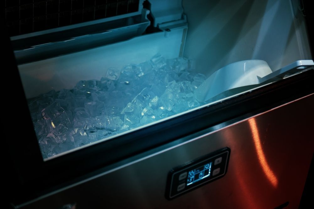 Ice machine filled with ice cubes, with a digital display and stainless steel exterior.