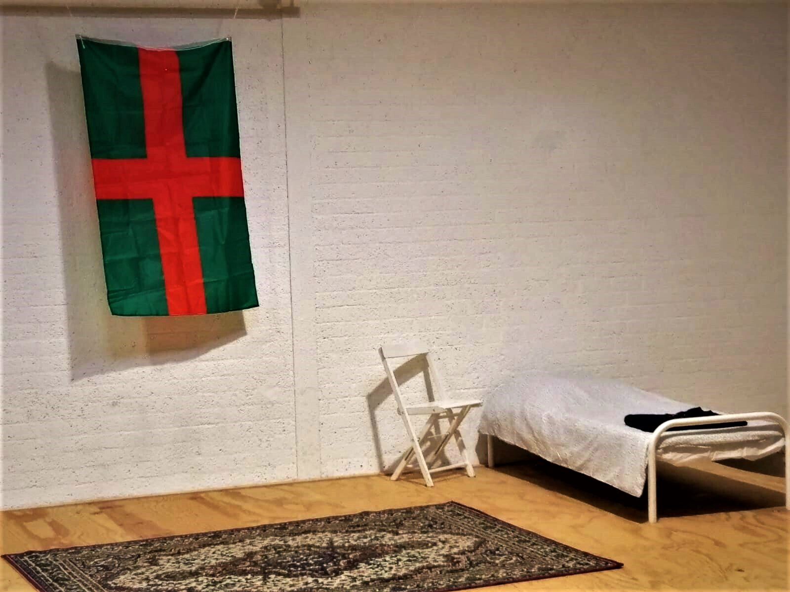 Opgemaakt bed met een stoel en vierdaagse vlag
