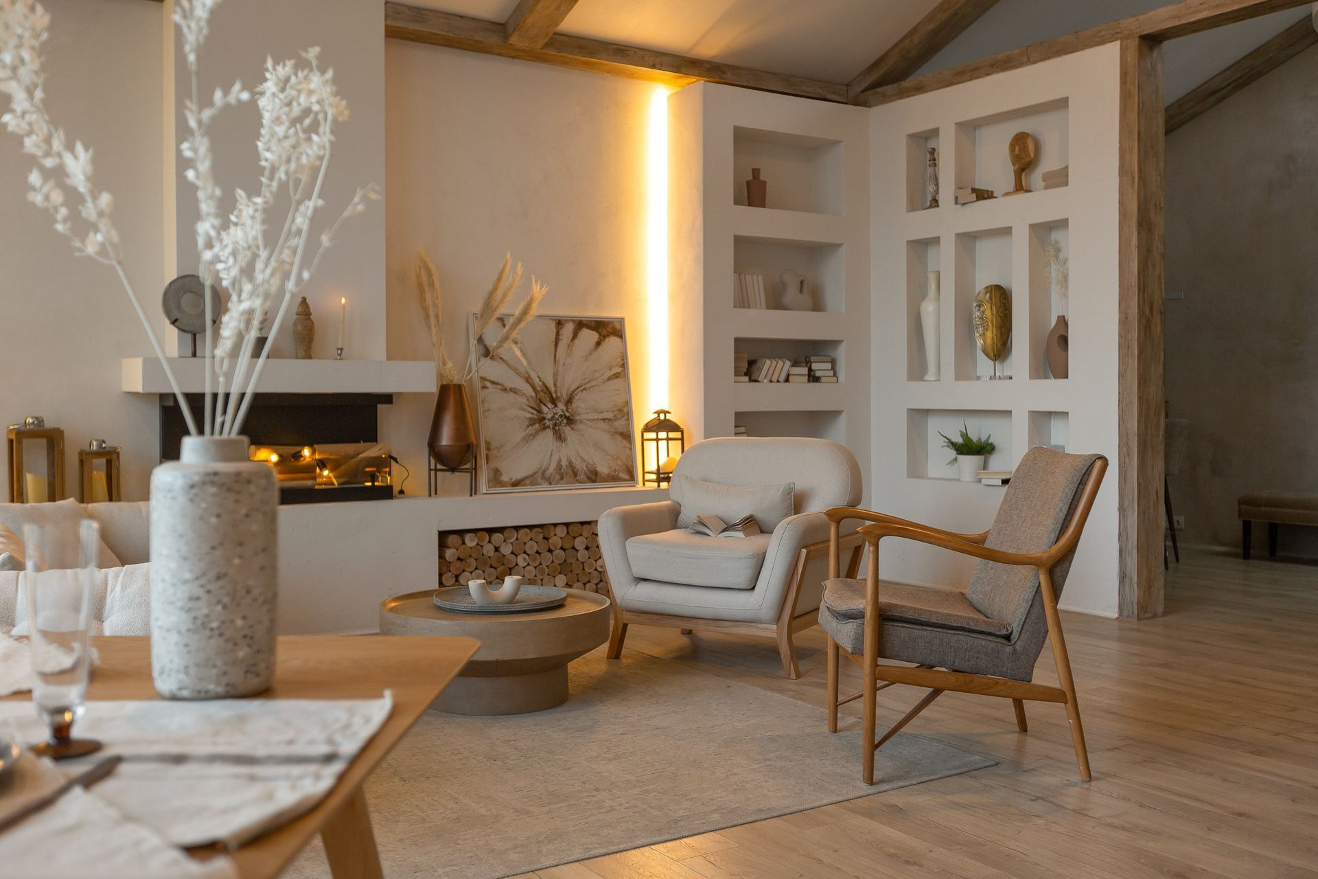 Cozy living room with fireplace, armchairs, wooden table, and neutral tones.