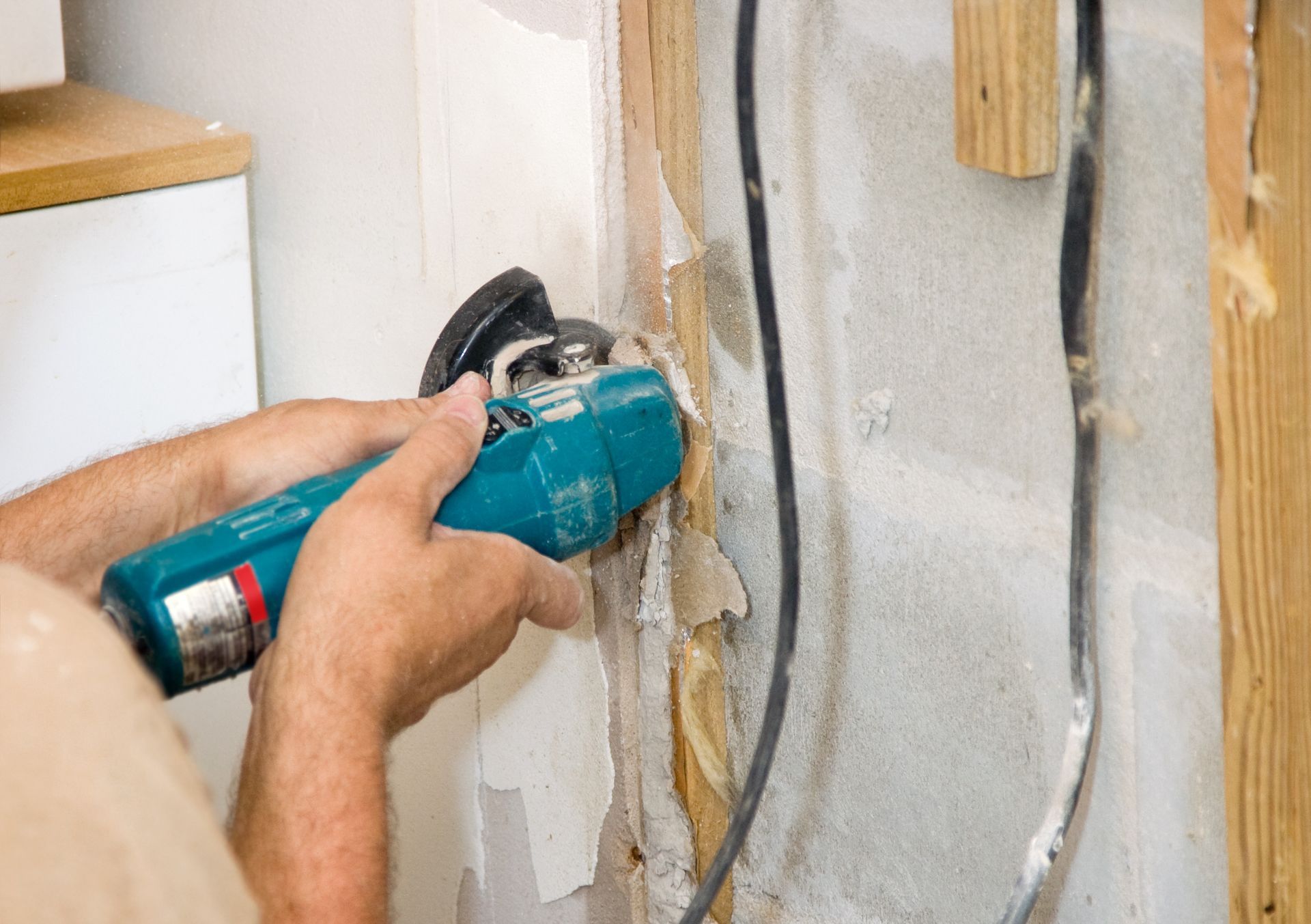 A man is using a circular saw to cut a hole in a wall.