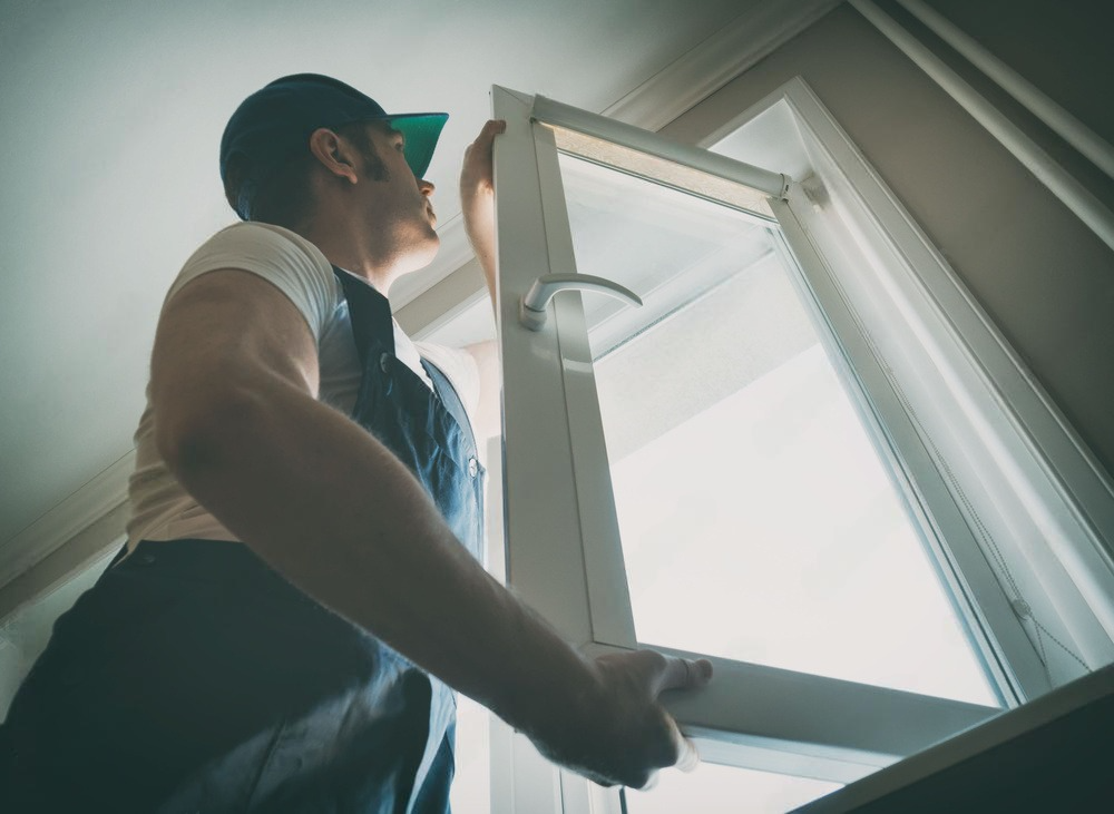 A man is opening a window in a room.
