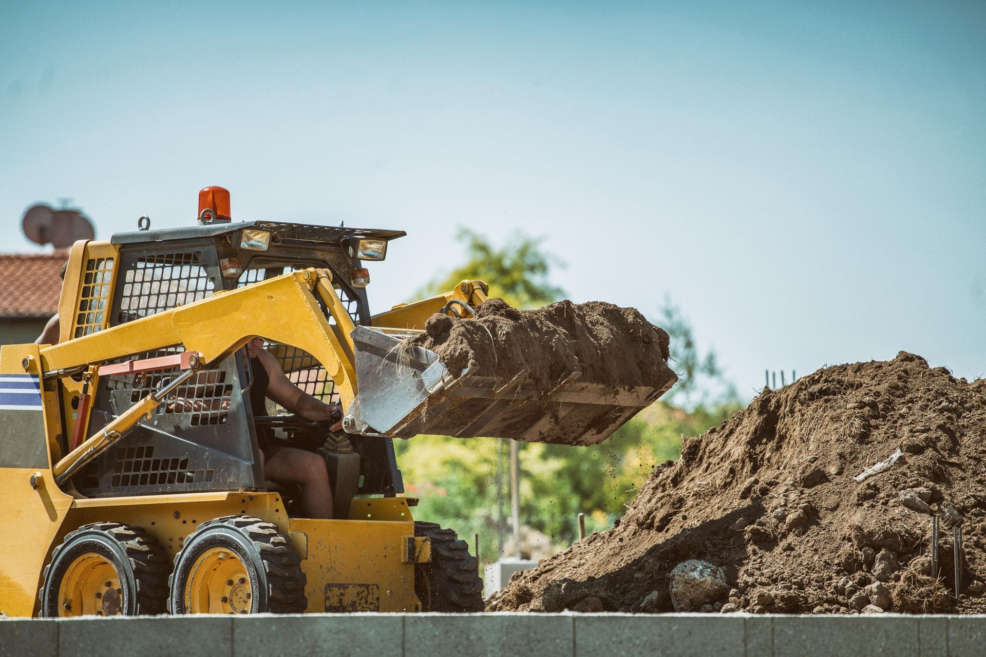 A bulldozer is loading dirt into a pile on a construction site.