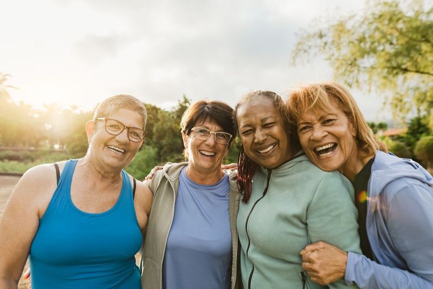 A group of older women are posing for a picture together in a park.