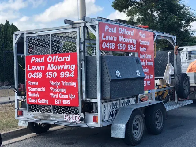 Red Riding Lawnmower Cutting Green Grass Beside A Curb — Paul Offord Mowing In Norman Gardens, QLD