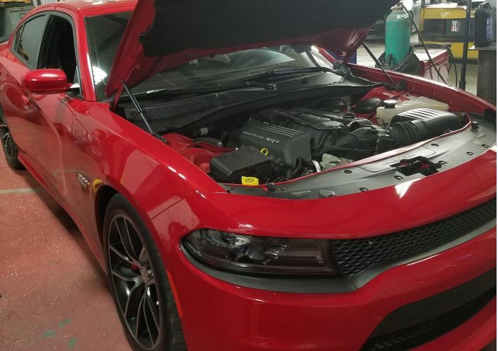 A red Dodge Charger with its hood open in a repair shop. | Integrated Automotive