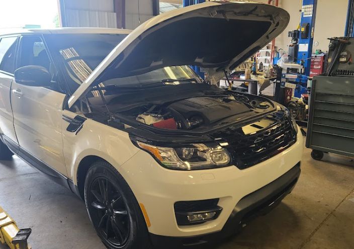 A white Range Rover with its hood open, parked inside an auto repair shop. | Integrated Automotive