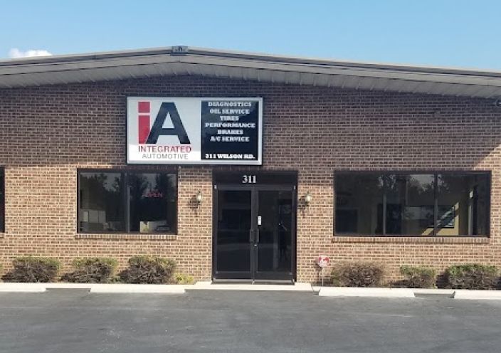 A brick building with an Integrated Automotive sign above the glass entrance doors and large windows on either side. | Integrated Automotive