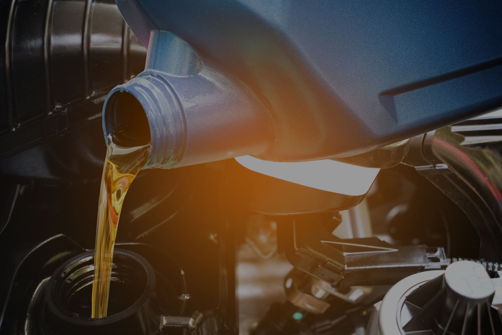 Oil pouring from a blue container into a car engine. | Integrated Automotive