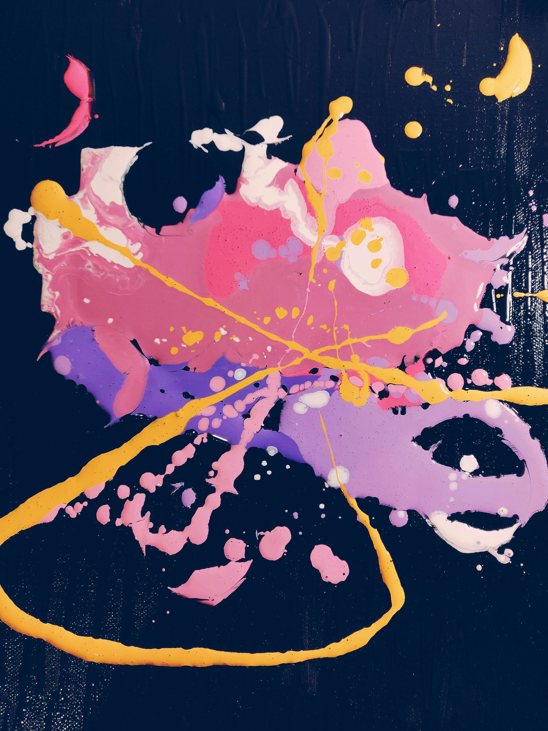 Abstract painting with pink, purple, and yellow paint splatters and swirling lines on a dark blue background.