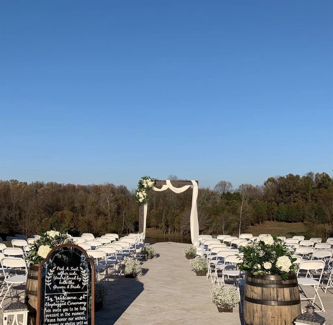 A wedding ceremony is taking place on a patio with a chalkboard and barrels. | Brookeville, MD | Silo Falls