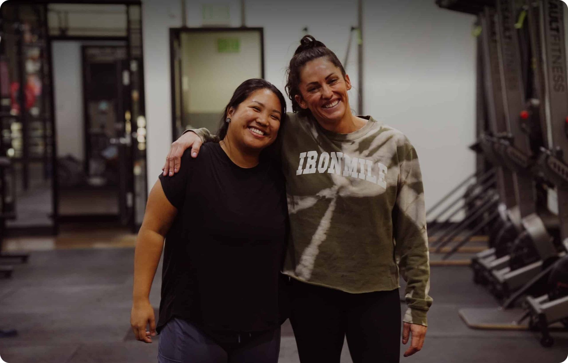 Two women smiling, arms around each other  at Iron Mile Fitness gym in Sacramento, CA