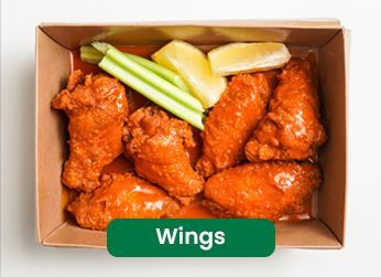 Buffalo wings in a cardboard container with celery and lemon wedges.