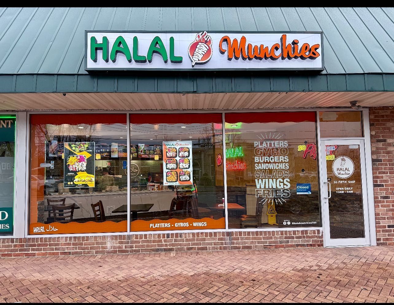Halal Munchies restaurant storefront with green and orange sign, glass windows, and brick exterior.
