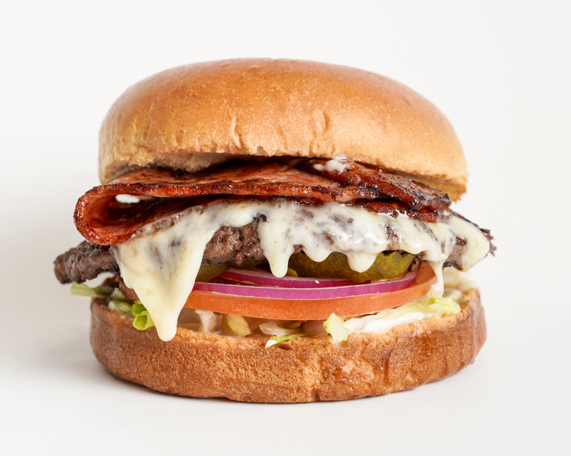 Hamburger on a toasted bun with bacon, cheese, tomato, onion, pickle, and lettuce.