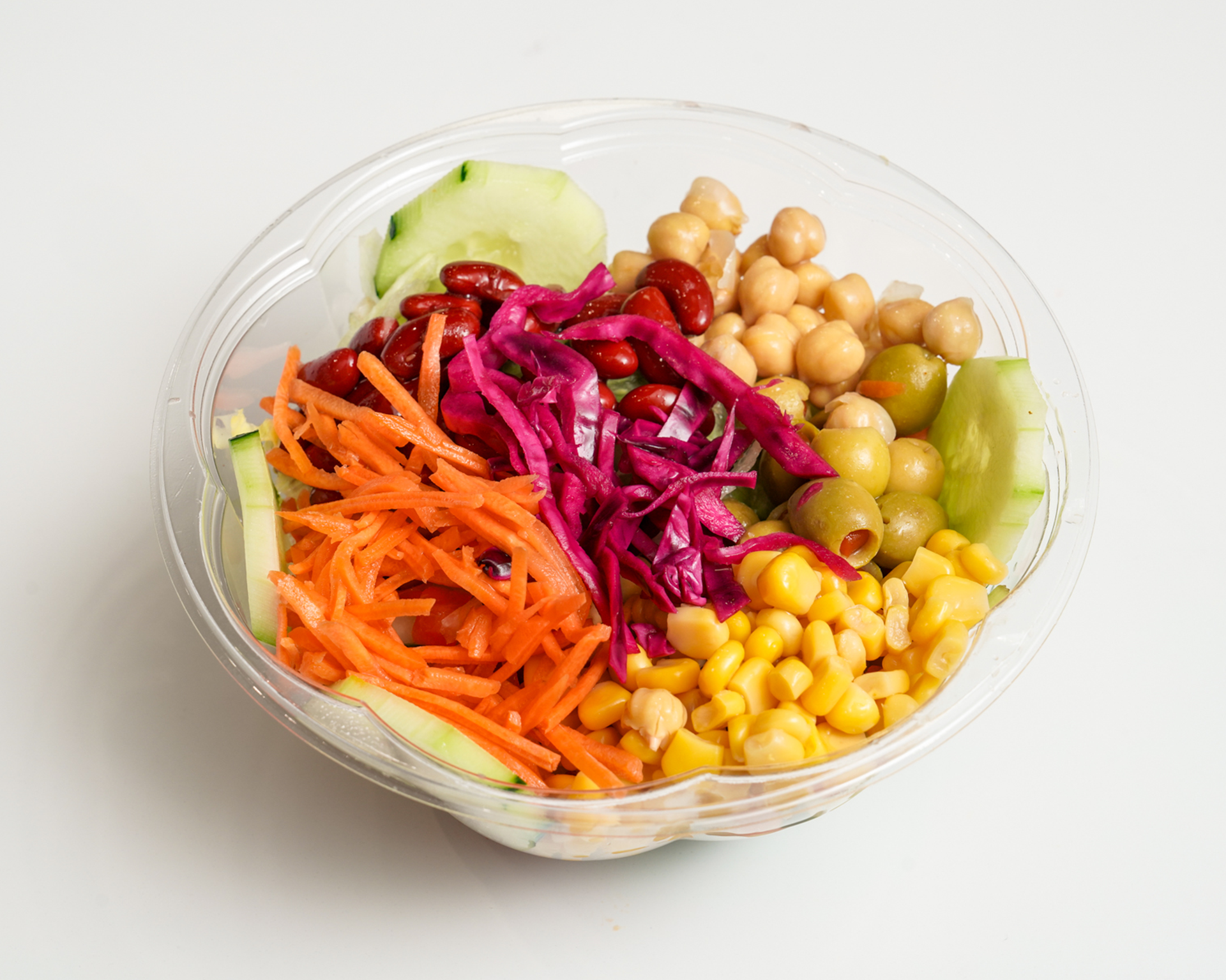 Salad bowl with shredded carrots, cabbage, chickpeas, olives, corn, cucumber, and beans.