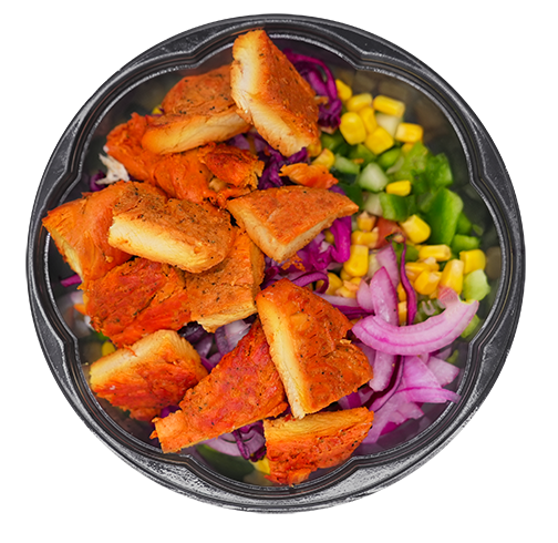 Bowl of salad with tofu, corn, red onion, green pepper, and red cabbage.