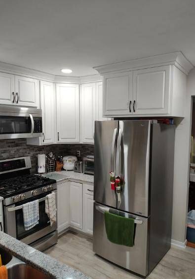 A kitchen with stainless steel appliances and white cabinets.