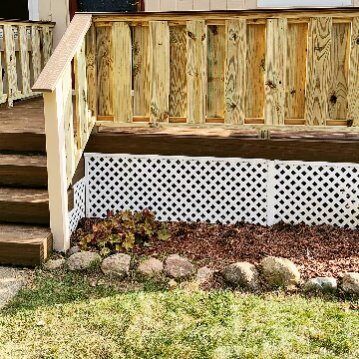 A wooden deck with stairs and a lattice fence surrounding it.