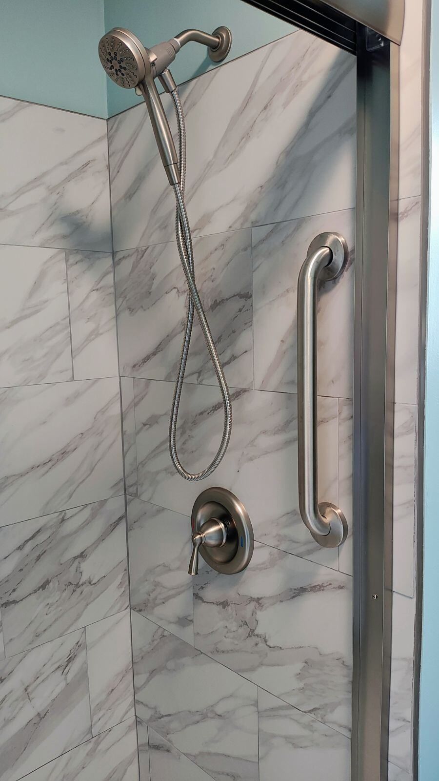 A shower with a hand rail and a shower head.