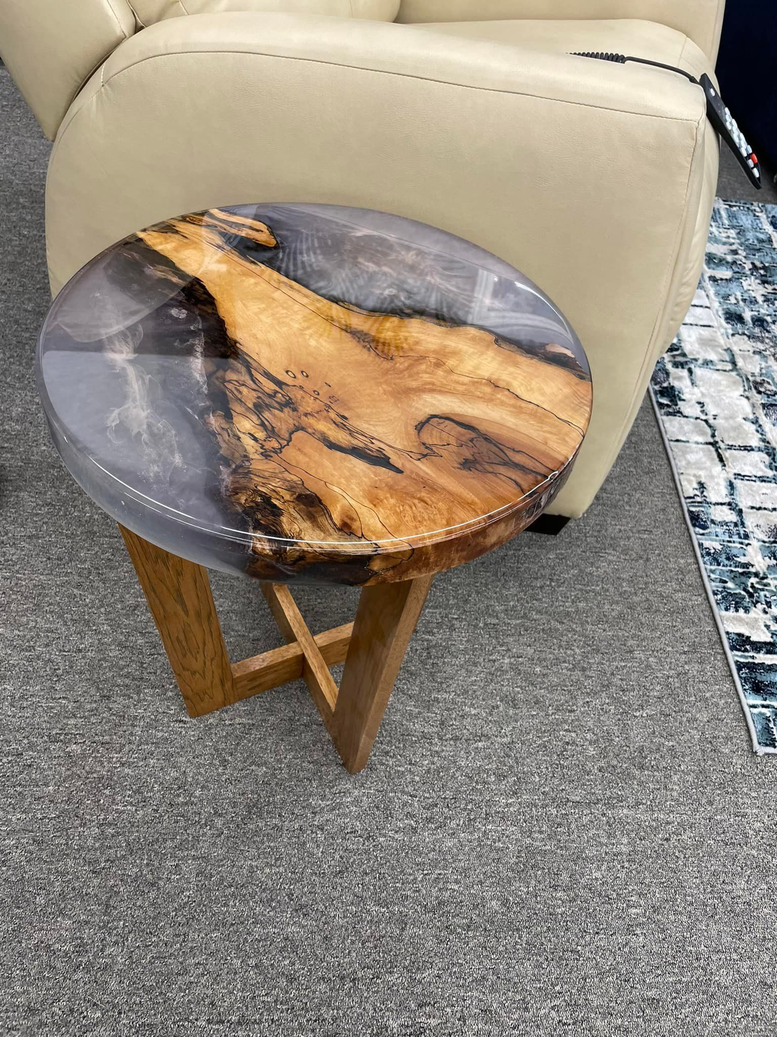 A small table made of wood and resin is sitting next to a chair.