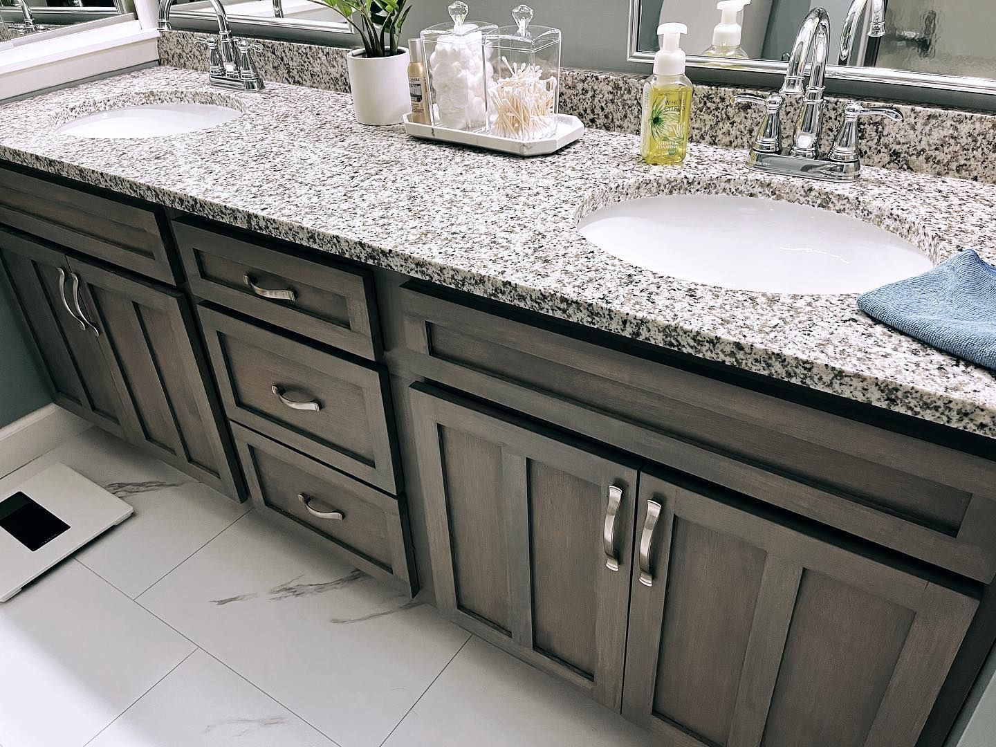 A bathroom with two sinks and a scale on the floor.