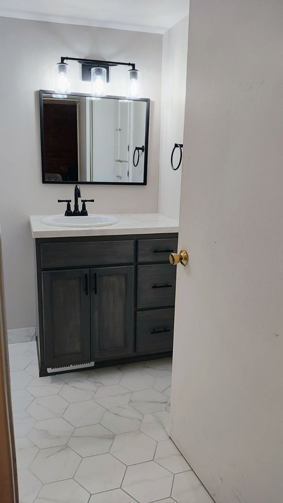 A bathroom with a sink , mirror , and drawers.